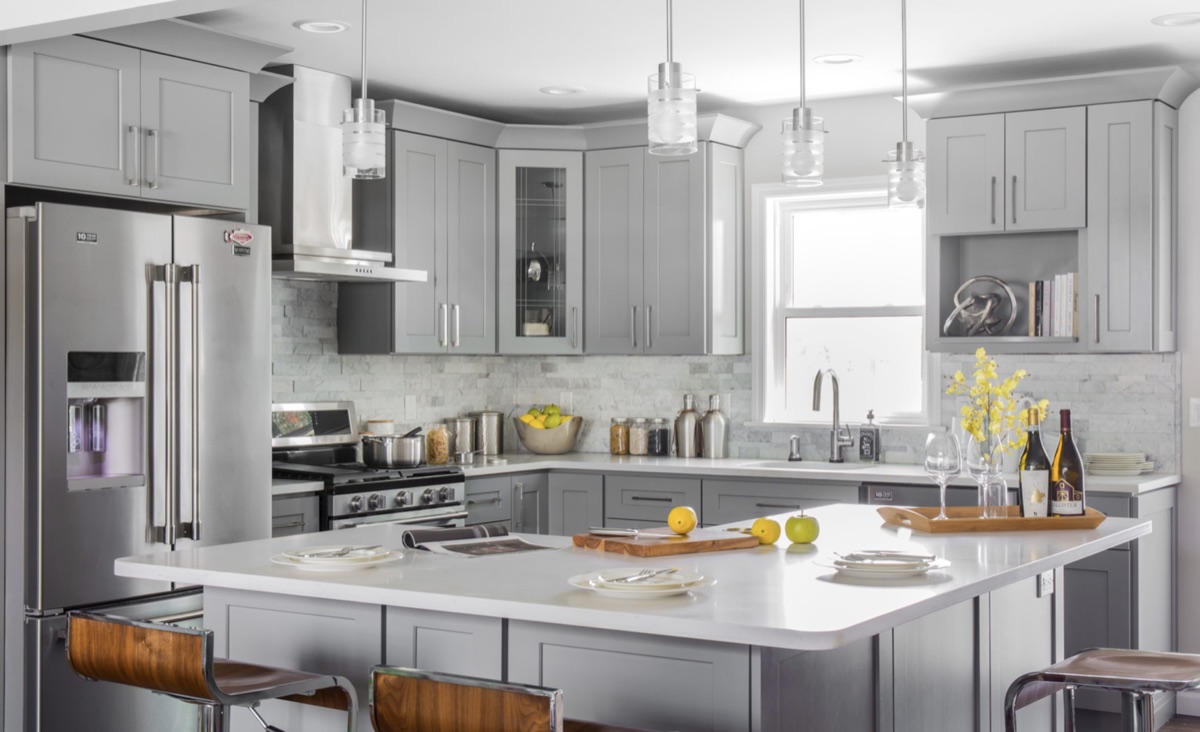 A remodelled grey shaker kitchen with a white quartz island and glass pendant lights.